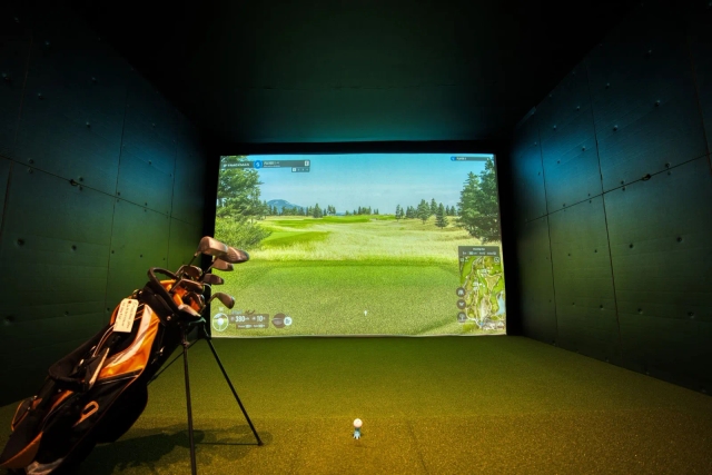 Golf bag and launch monitor inside the simulator bay, HD course projection on screen