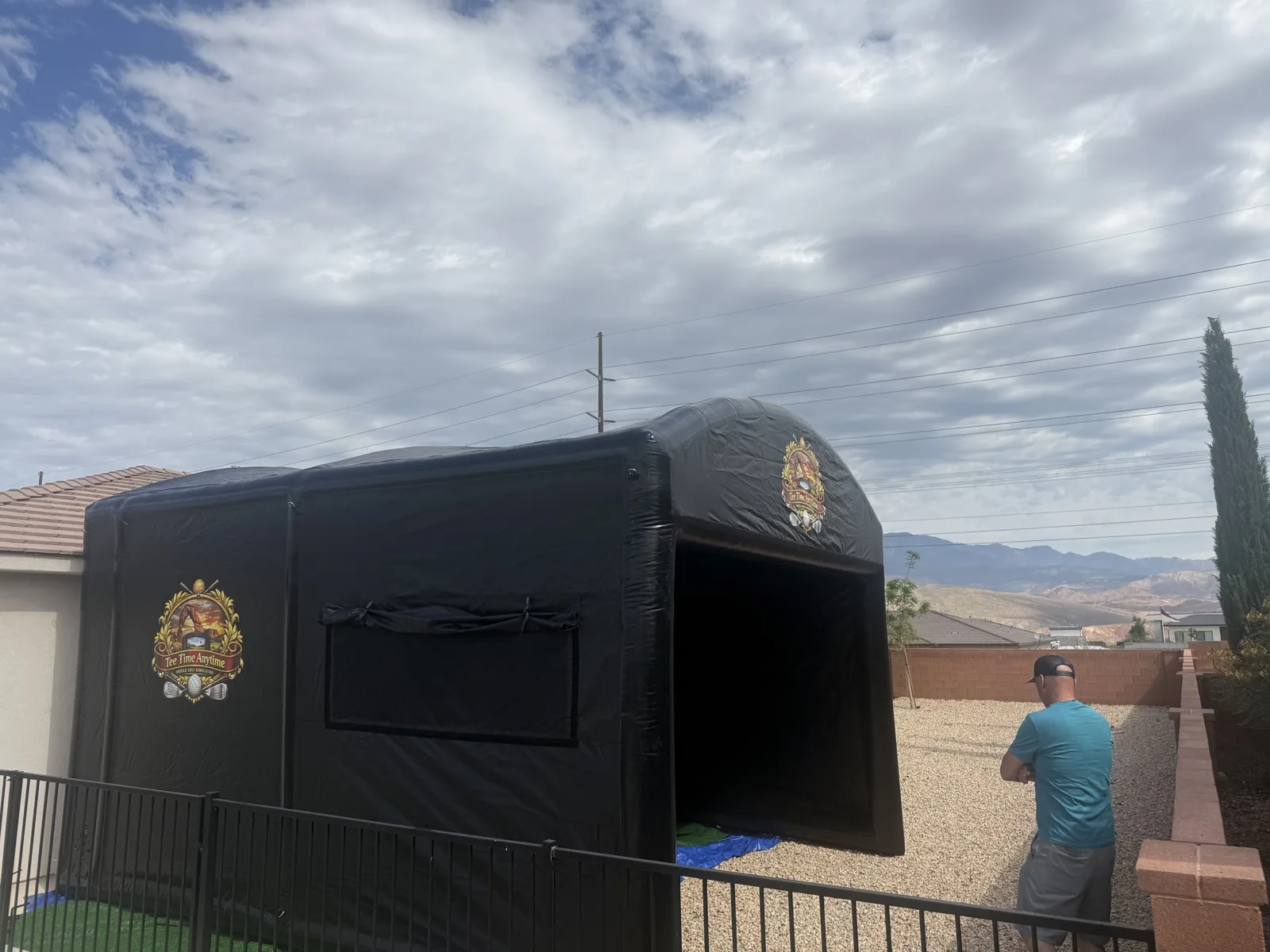 Inflatable golf simulator enclosure set up in a backyard, entrance open